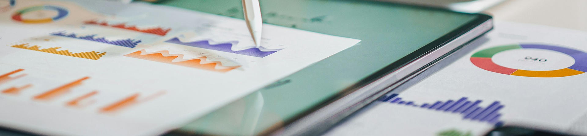 Photo of a report with infographics, a laptop, and a pencil tip